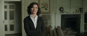 Movie still from “Mindhorn” (2016), directed by Sean Foley – A woman standing in front of a painting in a living room; Medium shot, Over the shoulder angle