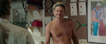 Movie still from “Mindhorn” (2016), directed by Sean Foley – A man with no shirt is smiling for the camera; Medium shot, Over the shoulder angle