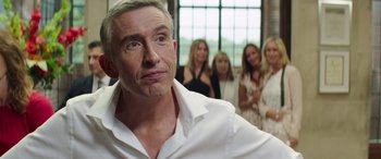 Movie still from “Mindhorn” (2016), directed by Sean Foley – A group of people standing around a man in a white shirt; Close Up shot, Over the shoulder angle