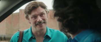 Movie still from “Mindhorn” (2016), directed by Sean Foley – A person wearing a blue shirt; Close Up shot, Over the shoulder angle