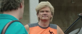 Movie still from “Mindhorn” (2016), directed by Sean Foley – A man with blonde hair wearing an orange shirt; Close Up shot, Over the shoulder angle
