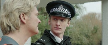 Movie still from “Mindhorn” (2016), directed by Sean Foley – A man in a police uniform talking to another man; Close Up shot, Over the shoulder angle