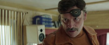 Movie still from “Mindhorn” (2016), directed by Sean Foley – A man wearing a brown leather jacket and a black eye patch; Close Up shot, Over the shoulder angle