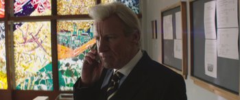 Movie still from “Mindhorn” (2016), directed by Sean Foley – A man in a suit and tie talking on a cell phone; Close Up shot, Over the shoulder angle
