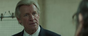 Movie still from “Mindhorn” (2016), directed by Sean Foley – An older man wearing a suit and tie; Close Up shot, Over the shoulder angle
