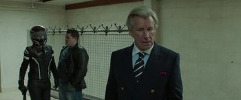 Movie still from “Mindhorn” (2016), directed by Sean Foley – An older man wearing a suit and tie; Medium shot, Over the shoulder angle