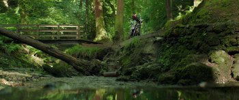 Movie still from “Mindhorn” (2016), directed by Sean Foley – A motorcycle is parked on the side of a river; Extreme Wide shot, Low angle
