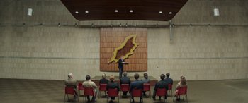 Movie still from “Mindhorn” (2016), directed by Sean Foley – A man giving a presentation to a group; Wide shot, High angle