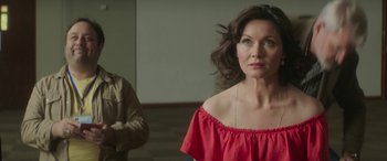 Movie still from “Mindhorn” (2016), directed by Sean Foley – A woman in a red top looking at a man in a brown jacket; Medium shot, Over the shoulder angle
