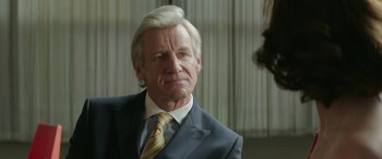 Movie still from “Mindhorn” (2016), directed by Sean Foley – An older man wearing a suit and tie; Close Up shot, Over the shoulder angle