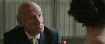 Movie still from “Mindhorn” (2016), directed by Sean Foley – An older man wearing a suit and tie looking at a woman; Close Up shot, Over the shoulder angle