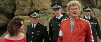 Movie still from “Mindhorn” (2016), directed by Sean Foley – A group of police officers standing next to each other near rocks; Medium shot, Over the shoulder angle