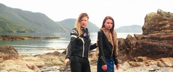 Movie still from “Mindhorn” (2016), directed by Sean Foley – Two women are walking on the beach near the water; Medium shot, Low angle