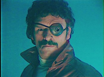 Movie still from “Mindhorn” (2016), directed by Sean Foley – A man with a beard and a mustache wearing glasses; Close Up shot, Low angle