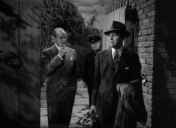 Movie still from “Ministry of Fear” (1944), directed by Fritz Lang – A group of men standing next to each other on a sidewalk; Medium shot, Low angle