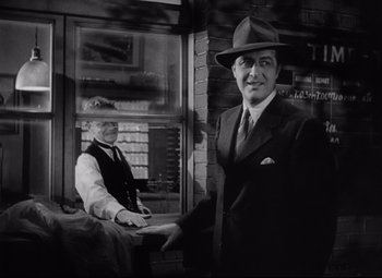 Movie still from “Ministry of Fear” (1944), directed by Fritz Lang – A man in a suit and hat standing next to a woman in a hat; Medium shot, Low angle