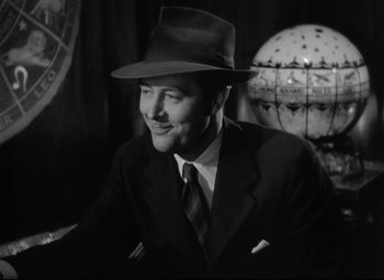 Movie still from “Ministry of Fear” (1944), directed by Fritz Lang – A black and white photo of a man wearing a suit and hat; Close Up shot, Low angle