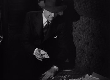 Movie still from “Ministry of Fear” (1944), directed by Fritz Lang – A black and white photo of a man in a suit and hat; Medium shot, High angle