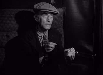 Movie still from “Ministry of Fear” (1944), directed by Fritz Lang – An old man sitting on a couch holding a cigarette; Medium shot, Low angle