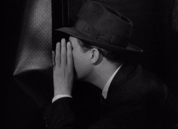 Movie still from “Ministry of Fear” (1944), directed by Fritz Lang – A black and white photo of a man in a suit and hat; Close Up shot, High angle