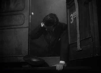 Movie still from “Ministry of Fear” (1944), directed by Fritz Lang – A black and white photo of a man leaning against a wall; Medium shot, High angle