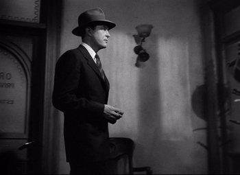 Movie still from “Ministry of Fear” (1944), directed by Fritz Lang – A black and white photo of a man in a suit and hat; Medium shot, Low angle