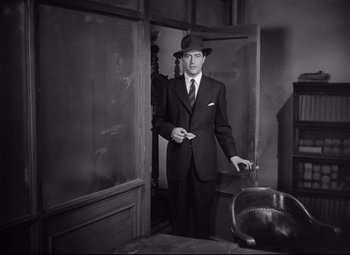 Movie still from “Ministry of Fear” (1944), directed by Fritz Lang – A black and white photo of a man in a suit and hat; Medium shot, Low angle