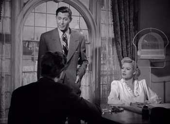 Movie still from “Ministry of Fear” (1944), directed by Fritz Lang – A black and white photo of a man and a woman in front of another man; Medium shot, Over the shoulder angle