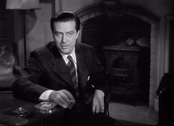 Movie still from “Ministry of Fear” (1944), directed by Fritz Lang – A black and white photo of a man sitting in a chair; Medium shot, Low angle