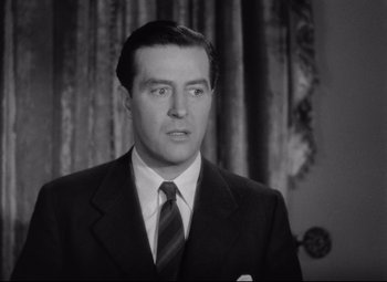 Movie still from “Ministry of Fear” (1944), directed by Fritz Lang – A black and white photo of a man wearing a suit and tie; Close Up shot, Low angle