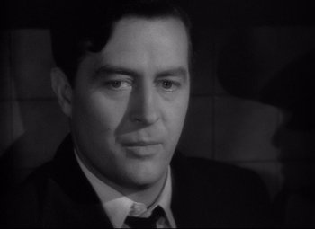 Movie still from “Ministry of Fear” (1944), directed by Fritz Lang – A black and white photo of a man in a suit and tie; Close Up shot, Over the shoulder angle