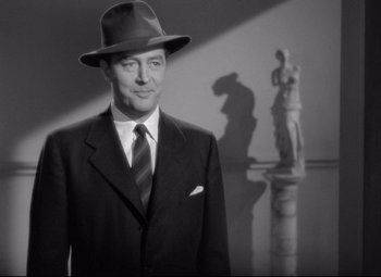 Movie still from “Ministry of Fear” (1944), directed by Fritz Lang – A black and white photo of a man wearing a suit and hat; Medium shot, Low angle