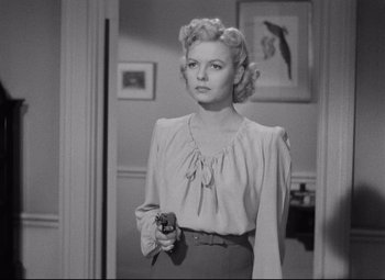 Movie still from “Ministry of Fear” (1944), directed by Fritz Lang – A black and white photo of a woman holding a gun; Medium shot, Over the shoulder angle