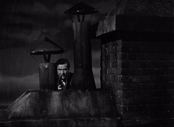 Movie still from “Ministry of Fear” (1944), directed by Fritz Lang – A black and white photo of a man looking over a wall; Wide shot, Low angle