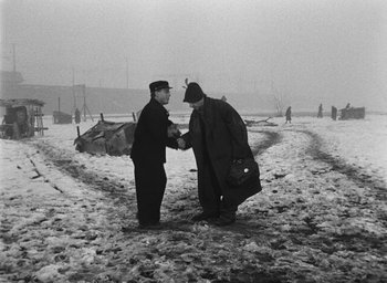 Movie still from “Miracle in Milan” (1951), directed by Vittorio De Sica – Two men shaking hands on a snowy day; Wide shot, High angle