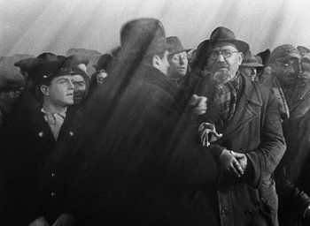 Movie still from “Miracle in Milan” (1951), directed by Vittorio De Sica – A group of men standing next to each other in a crowd; Medium shot, Over the shoulder angle