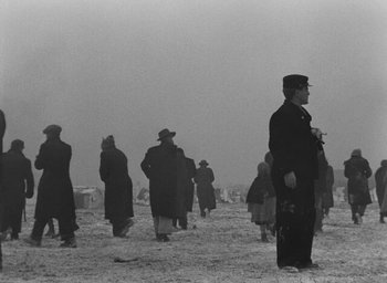 Movie still from “Miracle in Milan” (1951), directed by Vittorio De Sica – A black and white photo of people walking in the snow; Wide shot, Low angle