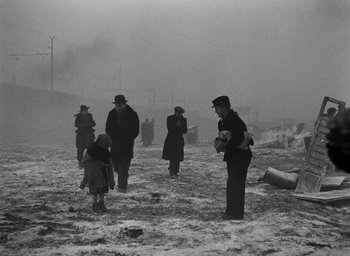 Movie still from “Miracle in Milan” (1951), directed by Vittorio De Sica – A black and white photo of people walking in the snow; Wide shot, High angle