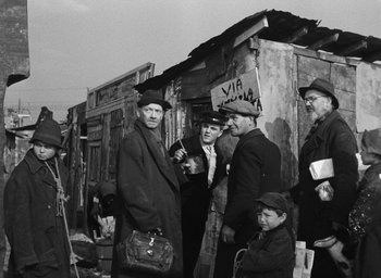 Movie still from “Miracle in Milan” (1951), directed by Vittorio De Sica – A group of people standing next to each other near a building; Wide shot, Over the shoulder angle