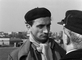 Movie still from “Miracle in Milan” (1951), directed by Vittorio De Sica – A man wearing a hat and a scarf; Close Up shot, Over the shoulder angle