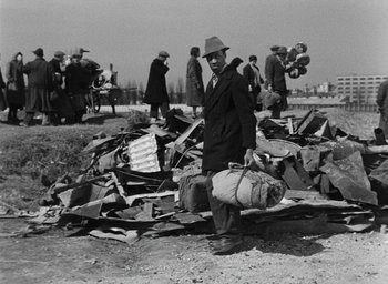 Movie still from “Miracle in Milan” (1951), directed by Vittorio De Sica – An old photo of a man standing in a pile of debris; Wide shot, High angle