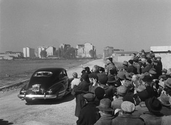 Movie still from “Miracle in Milan” (1951), directed by Vittorio De Sica – A crowd of people standing around a parked car; Extreme Wide shot, High angle