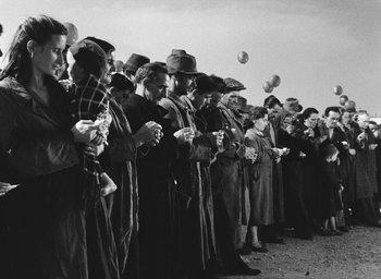 Movie still from “Miracle in Milan” (1951), directed by Vittorio De Sica – A group of people standing next to each other on a field; Wide shot, High angle