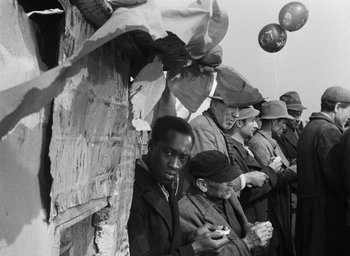 Movie still from “Miracle in Milan” (1951), directed by Vittorio De Sica – A group of men standing next to each other in front of a wall; Medium shot, Over the shoulder angle