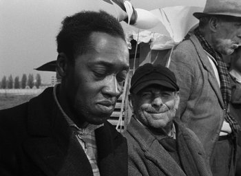 Movie still from “Miracle in Milan” (1951), directed by Vittorio De Sica – A man and an old man are standing together; Close Up shot, Over the shoulder angle