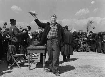 Movie still from “Miracle in Milan” (1951), directed by Vittorio De Sica – An older man holding a plate in his hand; Medium shot, Over the shoulder angle