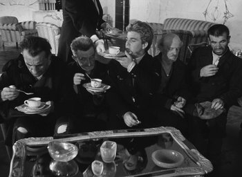Movie still from “Miracle in Milan” (1951), directed by Vittorio De Sica – A black and white photo of a group of people eating; Medium shot, High angle