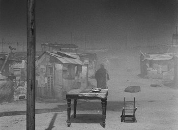Movie still from “Miracle in Milan” (1951), directed by Vittorio De Sica – A table and chair in the middle of a dust storm; Wide shot, High angle