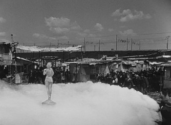 Movie still from “Miracle in Milan” (1951), directed by Vittorio De Sica – An old photo of a statue of marilyn monroe in the middle of a crowd; Extreme Wide shot, High angle