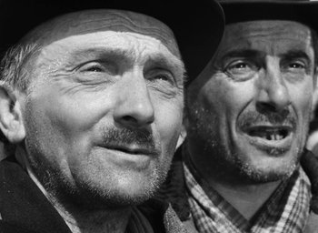 Movie still from “Miracle in Milan” (1951), directed by Vittorio De Sica – A black - and - white photo of two men in hats; Close Up shot, Low angle